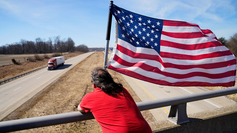 Mann mit USA-Flagge auf einer Brücke